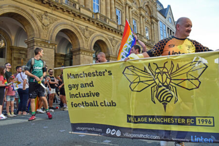 Manchester Greater Manchester UK August 24 2019 Pride parade passing in front of Radisson Hotel on Peter Street banner of Village Manchester FC football club with participants